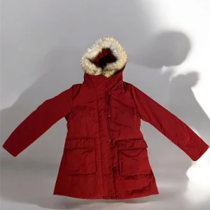 Röd parkajacka från Uniqlo - Säljer en snygg röd parkajacka från Uniqlo i storlek M. Jackan har en mysig fuskpälsfodrad huva och praktiska fickor framtill. Perfekt för kalla vinterdagar med sin varma vaddering och långa ärmar. Stängs med dragkedja och knappar för extra skydd mot kylan. 🧥❄️ Jackan är sparsamt använd enbart en säsong. 