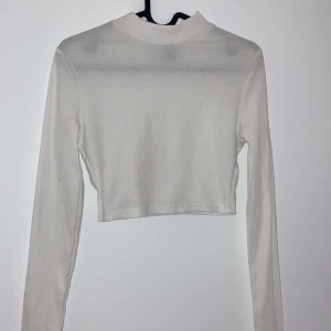 Vit croppad långärmad topp - Säljer en stilren vit croppad topp med långa ärmar. Perfekt för lager-på-lager eller att bära som den är. Enkel och snygg för både vardag och fest. Passar till allt! 🤍