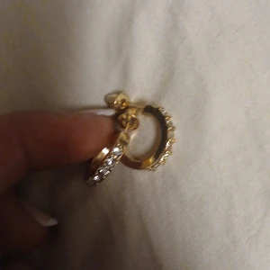 Guldörhängen med stenar - Säljer ett par eleganta guldörhängen med gnistrande stenar. De är i mycket bra skick och perfekta för att ge en touch av glamour till vilken outfit som helst. Passar både till vardag och fest!