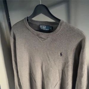 Grå tröja från Polo Ralph Lauren - Säljer en stilren grå tröja från Polo Ralph Lauren i storlek S. Tröjan är i bra skick och har en klassisk design.Perfekt för både höst och vinter som passar tills all tillfällen.