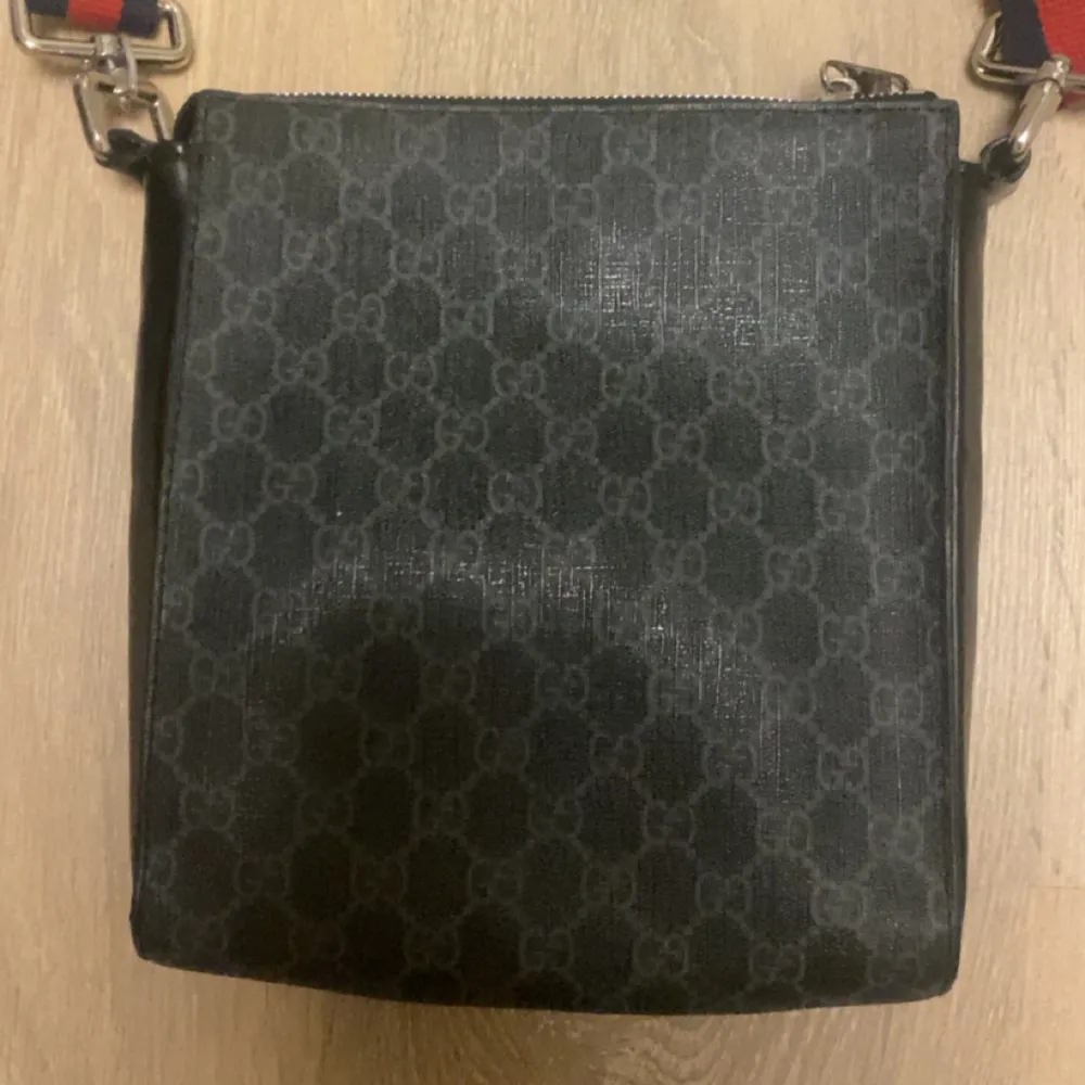 Säljer min snygga svarta crossbody väska från Gucci med klassiskt mönster. Väskan har använts fåtals gånger och är i mycket bra skick! Alexremmen är justerbar, den har 4 fack på insidan och ett på utsidan.. Väskor.