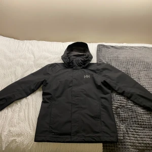 Helly Hansen Svart Jacka - Säljer en svart Helly Hansen jacka i mycket bra skick. Knappt använd, perfekt för höst och vår.  Möts endast i sthlm! Pris kan diskuteras. Ny pris 1800kr