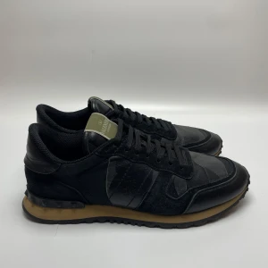 Valentino rockrunner  - Säljer ett par snygga svarta Valentino sneakers i skinn. De har en klassisk design med snörning och en bekväm sula i gummi. Perfekta för både vardag och fest! Skorna är i mycket bra skick och redo för nya äventyr. 41 passar 42