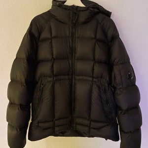 Svart dunjacka från C.P. Company - Säljer en svart dunjacka från C.P. Company i otroligt bra skick. Nypris är runt 7,5-8k. Jackan är inköpt förra året på NK och har hållit mig varm under vintern. Väldigt lätt i vikt men varm som bara den. Säljer för jag e sugen på nåt nytt. Inga defekter alls. Storlek 54, sitter som XL. Kan tänka mig att byta mot något intressant runt size M/L, så fråga gärna 😁Pris kan diskuteras