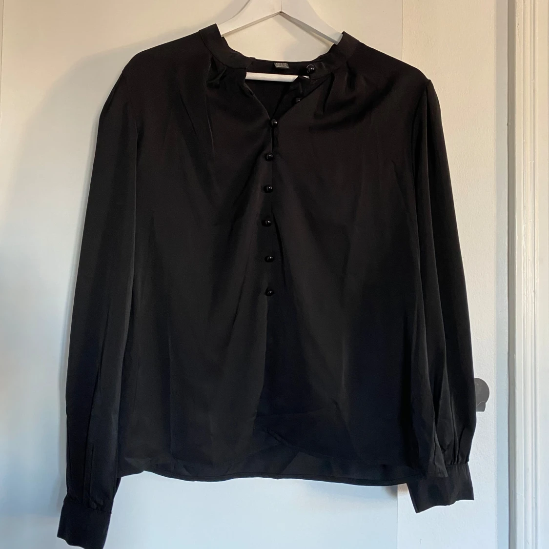 Svart blus med knappar.