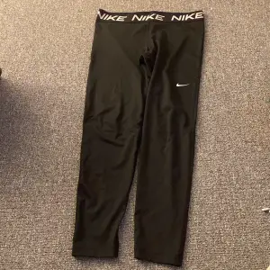 Säljer ett par svarta Nike leggings i mycket bra skick. De har en elastisk midja med Nike-loggan och en liten Swoosh på benet. Perfekta för träning eller vardagsbruk. Superbekväma och stilrena!