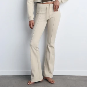 Beige mjukisbyxor  - Snygga beige byxor med hög midja och snörning i midjan. De har en bootcut-stil som ger en trendig look. Perfekta för både vardag och festliga tillfällen. Materialet ser mjukt och bekvämt ut, vilket gör dem till ett måste i garderoben! Köpa på Zara endast använda en gång
