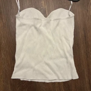 Vit ribbad korsettopp från Gina Tricot - Säljer en superfin vit ribbad korsettopp från Gina Tricot i storlek M. Toppen har smala axelband och en hjärtformad urringning som ger en snygg passform. Perfekt för sommarens fester eller en utekväll. Använd ett fåtal gånger och i mycket bra skick.