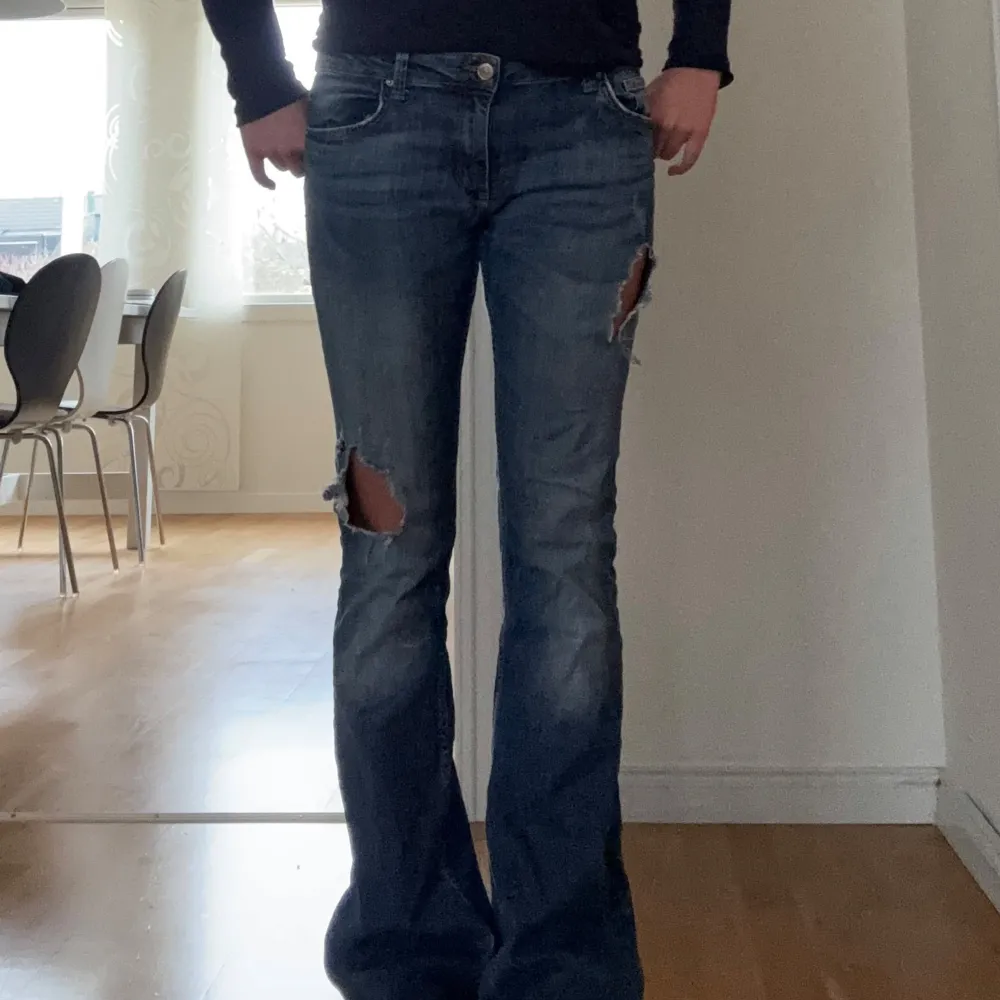 Säljer ett par snygga blå jeans med coola slitningar på låren. De har en lågmidjad passform och är i bootcut-stil. Köpta secondhand och har ingen lapp inuti. Som referens är jag 170 cm och har vanligtvis S/M i jeans. . Jeans & Byxor.