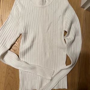 Vit ribbad tröja från Gina Tricot - Säljer en superfin vit ribbad tröja från Gina Tricot i storlek XS. Perfekt för både vardag och fest! Den har långa ärmar och en skön passform som sitter snyggt på kroppen. Passar perfekt till höst- och vinteroutfits. 🧡