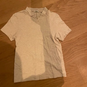 Beige kortärmad pikétröja - Säljer en stilren beige pikétröja i bra skick. Den har korta ärmar och en klassisk krage, perfekt för både vardag och lite finare tillfällen.