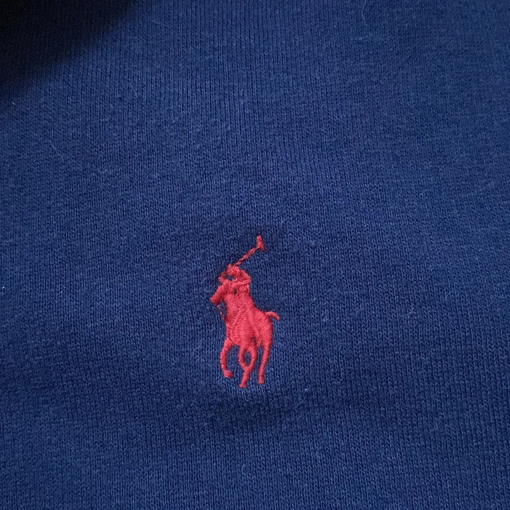 Säljer en snygg mörkblå tröja från Polo Ralph Lauren i storlek M. Tröjan har en halv dragkedja och det klassiska röda broderade logotypen på bröstet. Perfekt för både höst och vinter, och den är superbekväm att ha på sig. Passar till alla tillfällen!. Tröjor & Koftor.