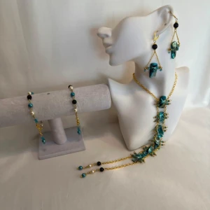 Turkos och guld smyckeset - Snyggt smyckeset med turkosa och svarta pärlor. Setet inkluderar ett halsband, armband och örhängen. Halsbandet har en unik design med turkosa stenar och guldkedja. Perfekt för att piffa upp en outfit till fest eller speciella tillfällen. Ett par örhängen och ett par armband plus en halsband handgjorda mycket mycket fint nytt oanvänd 