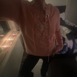 Rosa tröja med snörning - Säljer en snygg rosa tröja med cool snörning framtill. Perfekt för en avslappnad stil men ändå med en touch av något extra. Tröjan har långa ärmar och är superbekväm att ha på sig. Passar perfekt till både fest och vardags!