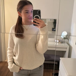 Beige stickad tröja - Mysig beige stickad tröja perfekt för kyliga dagar. Den har en avslappnad passform och långa ärmar, vilket gör den idealisk för både höst och vinter. Tröjan är enkel att matcha med olika outfits och ger en stilren look.