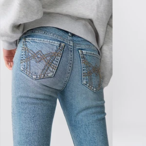 Blå jeans med broderade bakfickor - Snygga blå jeans med coola broderade detaljer på bakfickorna. De har en tight passform och är perfekta för både vardag och fest. Jeansen är i ett klassiskt denim-material och har en lågmidjad design. Perfekt för dig som vill ha en stilren men ändå unik look!