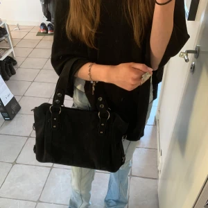 Svart axelväska med nitar - Snygg svart axelväska i mycket bra skick. Väskan har coola nitar och praktiska handtag, perfekt för vardagsbruk. Den är rymlig och stilren, får plats med dator och böcker!💗💞