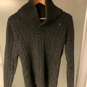 Mörkgrå stickad tröja med kabelmönster - Säljer en snygg stickad tröja från G star. Perfekt för höst och vinter! Säljer eftersom den är liten på mig. Tröjan är i bra skick och passar både till vardags och lite finare tillfällen. [Storlek L] [300kr]