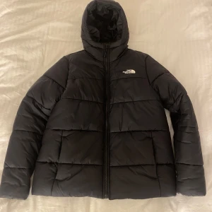 Svart vinterjacka från The North Face - Säljer en svart vinterjacka från The North Face i storlek L. Jackan är perfekt för kalla vinterdagar med sin tjocka vaddering och huva. Den har en dragkedja framtill och är i mycket bra skick. Passar både till vardags och utomhusaktiviteter. Fler bilder finns men fick max lägga ut 5, skriv privat eller kolla Vinted liinarlarsson 💗