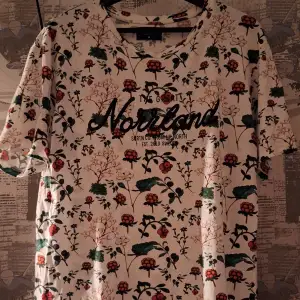 Säljer en superfin vit t-shirt från The Great Norrland med ett färgglatt blommigt mönster. Knappt använd och i supergott skick.