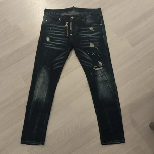 Jeans från Dsquared2 - Säljer två par snygga jeans från Dsquared2. Ett par i mörkblått med slitningar och ett par i svart med lätt tvättad look. Båda har en tight passform och är perfekta för en trendig vardagsstil. Tillverkade i Italien med hög kvalitet. Perfekta för höst och vår!
