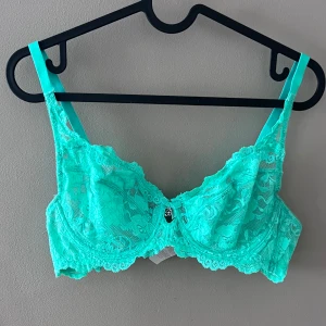 Turkos spets-bh - Säljer en superfin turkos spets-bh med justerbara axelband och en liten dekorativ detalj framtill. Den har en klassisk hakknäppning bak och är i mycket bra skick. Perfekt för att lägga till lite färg i garderoben!