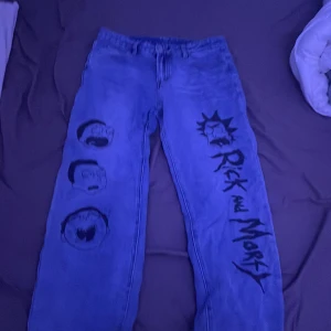 Blå jeans med Rick and Morty-motiv - Säljer ett par unika blå jeans med coolt Rick and Morty-tryck. De har en loose passform och är perfekta för fans av serien. Jeansen har tryck av karaktärerna på framsidan och är i bra skick. Perfekta för en avslappnad stil eller för att sticka ut på en fest!