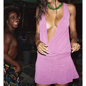 Lila omlottklänning - Snygg lila omlottklänning med djup v-ringning och ärmlös design. Perfekt för sommarens fester eller en dag på stranden. Klänningen har en kort längd och en avslappnad passform. Från bambaswin. Nyskick! 