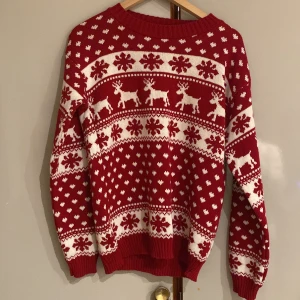 Röd jultröja med renar och snöflingor - Supermysig röd jultröja med vita renar och snöflingor. Perfekt för julmys och kalla vinterdagar. Tröjan är stickad och har långa ärmar med ribbstickade muddar. Ett måste för julstämningen! 🎄är använd vid två tillfällen och sticks inte. I storleken s men passar även m. Från JFR
