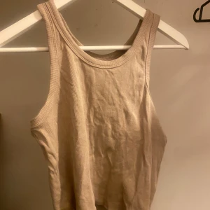 Beige ribbad linnetopp från lager 157 - Säljer en snygg beige ribbad linnetopp från lager 157 i storlek XL. Perfekt för sommardagar eller som ett basplagg i garderoben. Toppen är ärmlös och har en  rund halsringning.