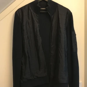 J.Lindeberg cardigan  - Säljer en snygg svart jacka från J.Lindeberg i storlek M. Jackan har en quiltad design med dragkedja och en metall logga på ärmen. Perfekt för höst och vår🍁Den är bekväm och i fint skick🌟Byten av rockar och dunjackor är intressant🙏🏼