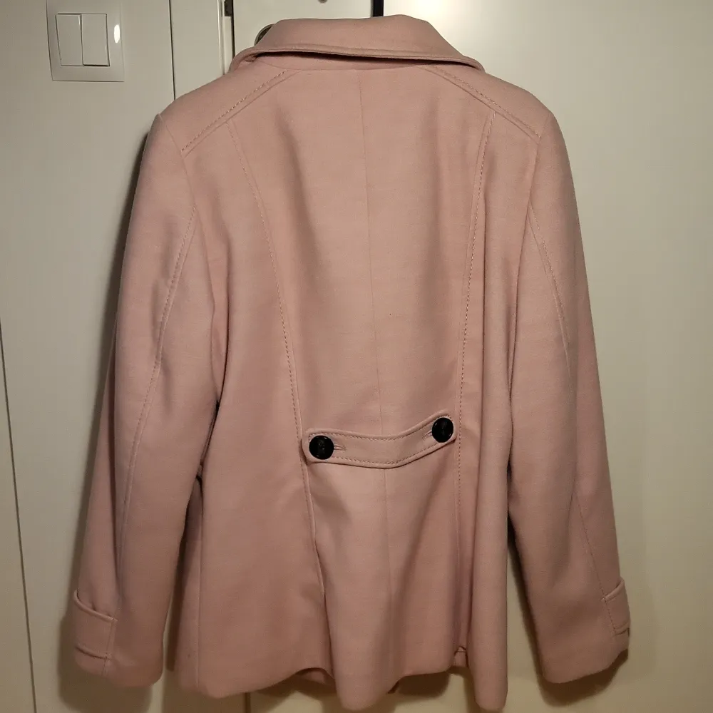 Säljer en superfin rosa kappa från H&M i storlek 40. Den har en dubbelknäppt design med svarta knappar och en stilren krage. Perfekt för höst och vår, och ger en elegant touch till vilken outfit som helst. Kappan är i mycket bra skick och redo för nya äventyr!. Jackor.