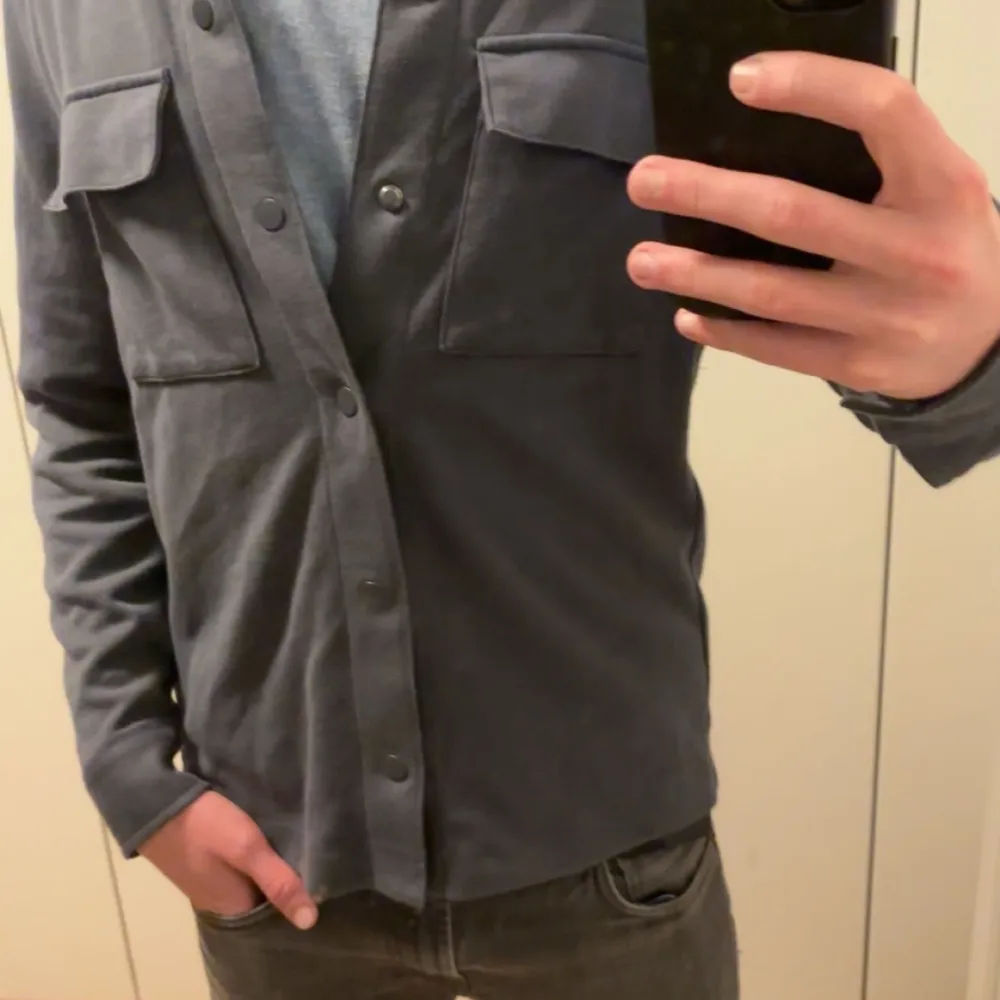 Säljer en snygg mörkblå overshirt med knappar framtill. Den har två bröstfickor med lock och är perfekt för lager-på-lager-stil. Passar både till vardags och lite mer uppklädda tillfällen. Perfekt för höst och vår!. Jackor.