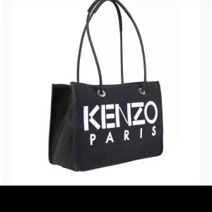 Svart axelväska från Kenzo - Snygg svart axelväska från Kenzo med stort vitt tryck. Väskan har långa handtag och en praktisk dragkedja inuti. Perfekt för både vardag och fest! 🖤 priset kan diskuteras något 