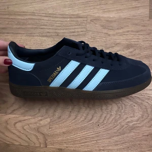 Adidas Spezial sneakers - Säljer ett par snygga Adidas Spezial sneakers i mycket bra skick. Skorna är mörkblå med ljusblå ränder och har en klassisk design. Perfekta för både vardag och fest! De har en bekväm passform och är tillverkade i syntetmaterial. Helt nya!🫶🏽 kommer i originalförpackning