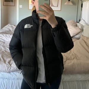North Face puffer jacket - Säljer en svart dunjacka från The North Face i mycket bra skick. Jackan har en dragkedja framtill och två praktiska fickor med dragkedja. Perfekt för kalla vinterdagar och håller dig varm och bekväm! 😍 Jackan är i mycket fint skick, finns inget att anmärka på. Den är köpt på barnavdelningen i strl 152. Skulle säga att den motsvarar en XS. Jag är 165 lång! Säljer pga att den är lite för liten för mig! Använd 3 säsonger.🩵