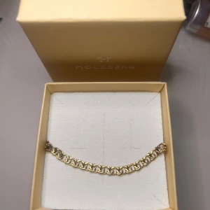 Guldarmband från Mockberg - Snyggt guldarmband från Mockberg i en elegant kedjedesign. Perfekt för att ge en touch av lyx till vilken outfit som helst. Kommer i originalförpackning, vilket gör det till en fin presentidé. Passar både till vardags och festliga tillfällen. Orginalpris 699kr. 