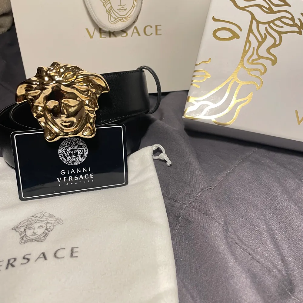 Säljer ett snyggt svart skärp från Versace med ett stort, ikoniskt guldspänne i form av Medusa. Perfekt för att ge din outfit en lyxig touch. Skärpet är i nytt skick och kommer med originalförpackning och påse. Passar både till fest och vardag.. Accessoarer.