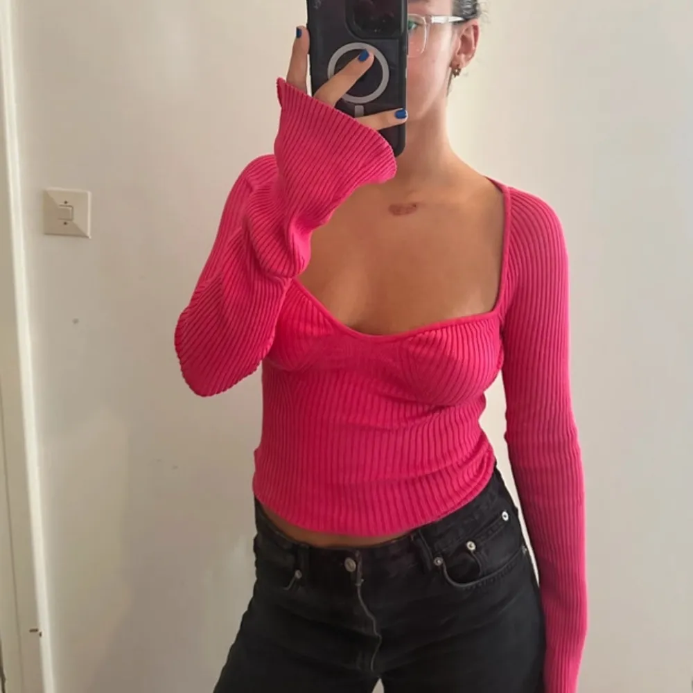 Säljer en snygg rosa ribbad topp med långa ärmar och en unik omlott-design framtill. Toppen är tight och perfekt för både vardag och fest. Den har en djup urringning som ger en trendig look. Passar perfekt till jeans eller kjol!. Neuleet.