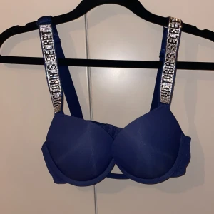 Blå bh från Victoria's Secret - Snygg blå bh från Victoria's Secret med glittriga axelband som ger en extra touch av glamour. ALDRIG använd, då jag råkat beställa fel strlk, strlk 75b( har även likadana i röd, blå och rosa 
