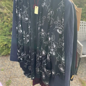 Svart blommig kavaj från Rembrandt - Snygg svart kavaj med vita blommor från Rembrandt. Perfekt för både fest och vardag. Den har en elegant design med ett blommigt mönster som ger en stilren look. Passar bra till både jeans och mer formella byxor.