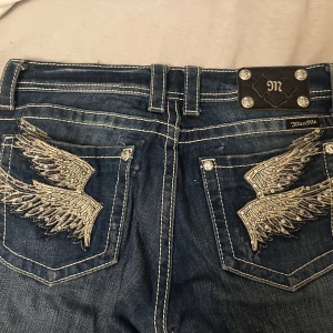 Super snygga Miss Me jeans 💕 - Säljer ett par snygga blå jeans från Miss Me i storlek 28. De har super fina vingar på bakfickorna och snygga knappar. Jeansen är i modellen straight men sitter som bootcut när min kompis testade dom, då de är förstora för mig tyvärr. Köpte dom för 1600kr. Aldrig använt dom. Har inte symaskin eller något liknande så kan inte sy upp och dom själv. Normal i storleken eller något snäpp mindre. Skriv om ni har frågor 💕