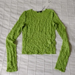 Grön långärmad spetstopp/tröja i spets från Bik Bok - long sleeve  - Säljer en superfin grön spetstopp från Bik Bok. Den är långärmad i en cool design med diagonala sömmar. Perfekt för både vardag och fest 💚