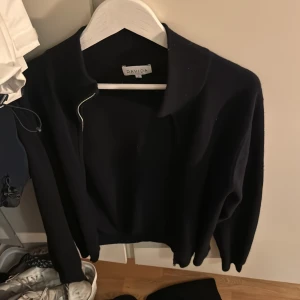 Mörkblå tröja från Davida - Säljer en stilren svart tröja från Davida i storlek L. Tröjan har en klassisk design med långa ärmar och en mjuk känsla, perfekt för både vardag och lite finare tillfällen. Passar bra till höst- och vintergarderoben.