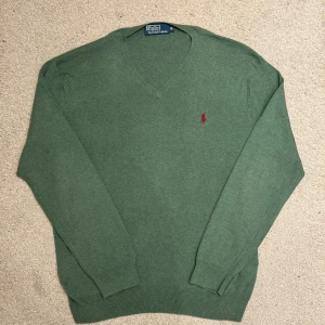 Grön Tröja från Polo Ralph Lauren - Märke: Polo Ralph Lauren Storlek: M Färg: Grön Skick: Mycket bra skick Detaljer: Klassisk V-ringad design med röd Polo-logga på bröstet