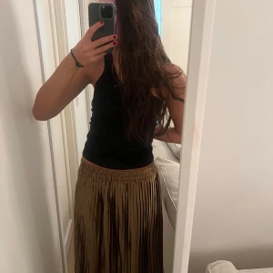 Guldig plisserad långkjol - Säljer en superfin guldig plisserad långkjol som är perfekt för både fest och vardag. Kjolen har en elastisk midja för en bekväm passform och ett elegant fall. Den glänsande guldiga färgen gör den till ett statement-plagg i garderoben. Passar perfekt till en enkel topp eller en festlig blus. 🥳✨