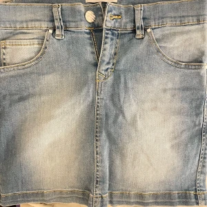 Ljusblå jeanskjol - Säljer en superfin ljusblå jeanskjol i kort modell. Den har en klassisk femficksdesign med snygga sömmar och en dragkedja framtill. Perfekt för sommardagar eller en avslappnad vårlook. Passar till allt från sneakers till sandaler!