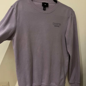 Lila sweatshirt från Worldly - Säljer en snygg lila sweatshirt från Worldly i storlek M. Tröjan har ett coolt tryck på ryggen med texten 'Worldly' och en jordglob. Perfekt för en avslappnad stil och passar bra till både jeans och joggers. Den är i mycket bra skick och redo för nya äventyr!