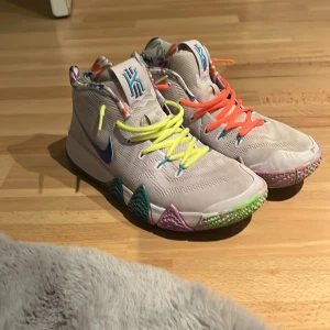 Färgglada sneakers från Nike - Säljer ett par unika sneakers från Nike med en mix av färgglada detaljer. Skorna har en vit bas med blå swoosh( som jag har målat på själv med tusch) och flerfärgade snören i gult och orange. Sulan är mönstrad i olika färger och insidan har ett livligt mönster. Perfekta för dig som vill sticka ut!