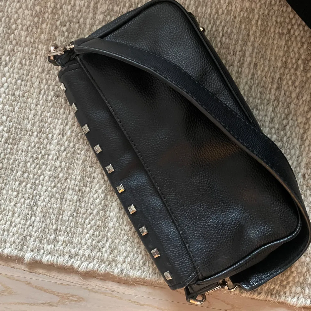 Svart väska från Guess med nitar, lång och kort band medkommer. Köpt för 1000kr säljer för 400. Laukut & Käsilaukut.